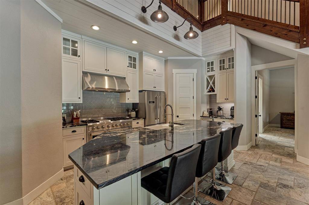 The kitchen is as functional as it is beautiful, featuring a spacious corner pantry that offers ample room for dry goods and kitchen essentials. Thoughtfully designed glass-front cabinets add a touch of elegance and are perfect for displaying fine dishware or collectibles. Custom wine storage provides a stylish and practical solution for wine enthusiasts.