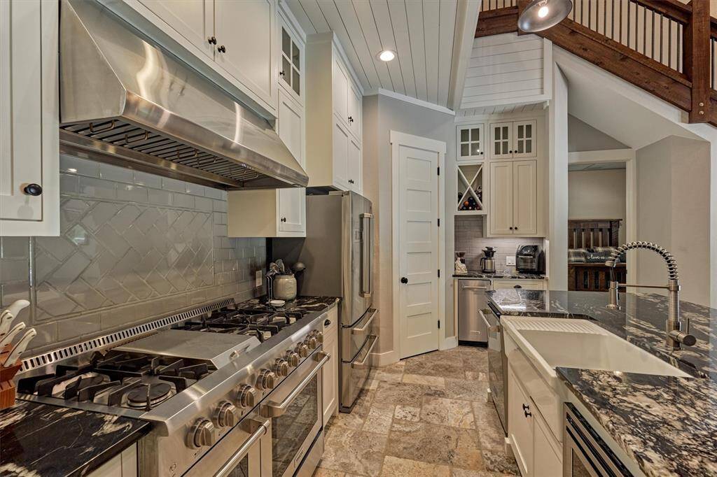 Luxury Thor appliances make this kitchen a chef’s dream. The professional-grade six-burner gas stove with griddle and dual ovens is perfect for preparing meals for a crowd or hosting holiday gatherings. A stylish farmhouse sink with apron front includes a built-in drainboard for added convenience. Additional stainless steel appliances include a built-in microwave, dishwasher, and dedicated ice maker, all combining to create a functional and luxurious culinary space.