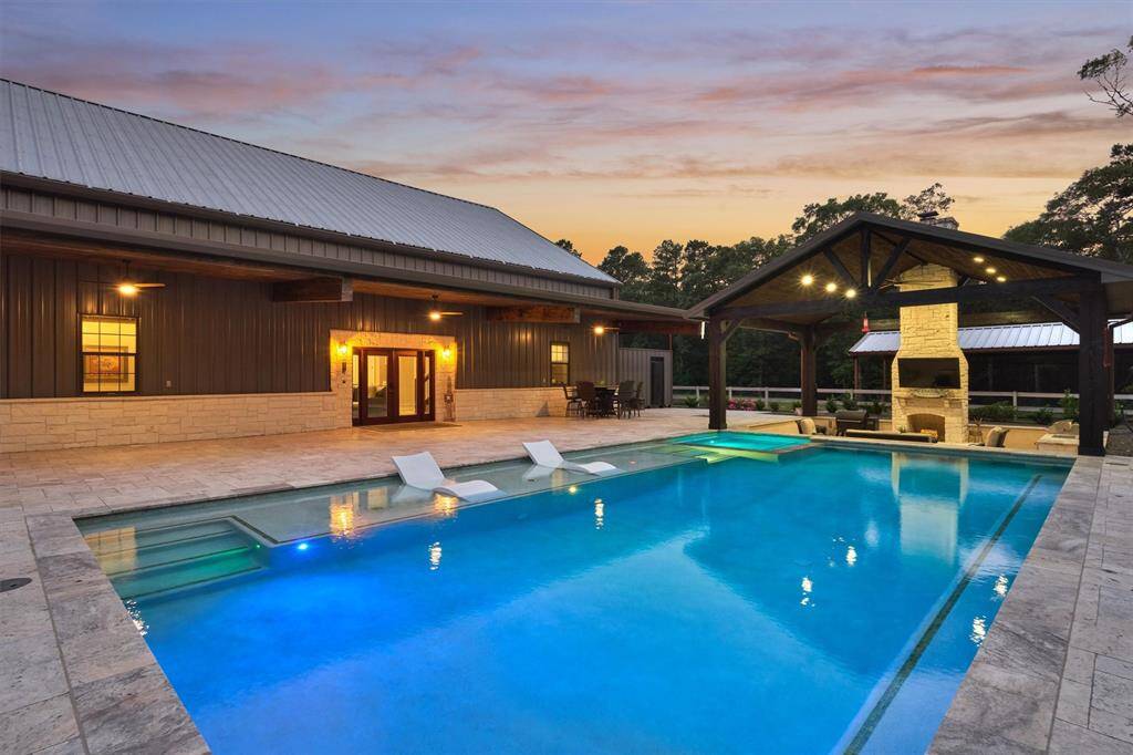 Two sets of steps flank the tanning ledge for easy access into the pool, while a hot tub anchors the far end. A built-in bench on the opposite side creates the perfect spot for relaxing and enjoying conversation with family and guests.