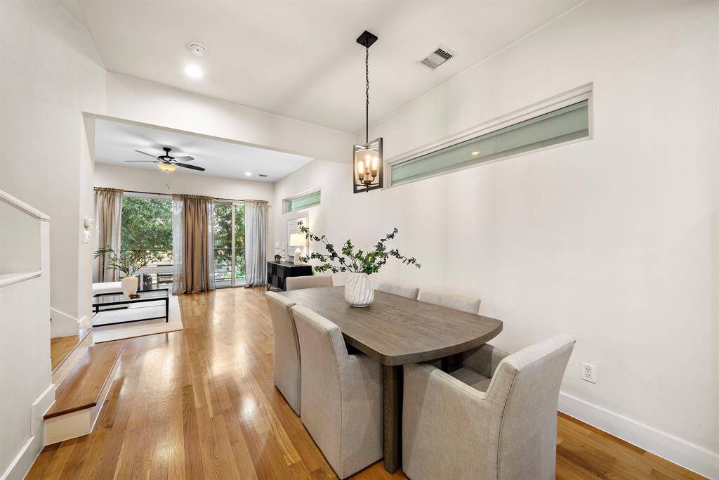Defined by an inviting blend of openness and style, the dining area seamlessly connects to the spacious living room with hardwood floors and modern lighting.