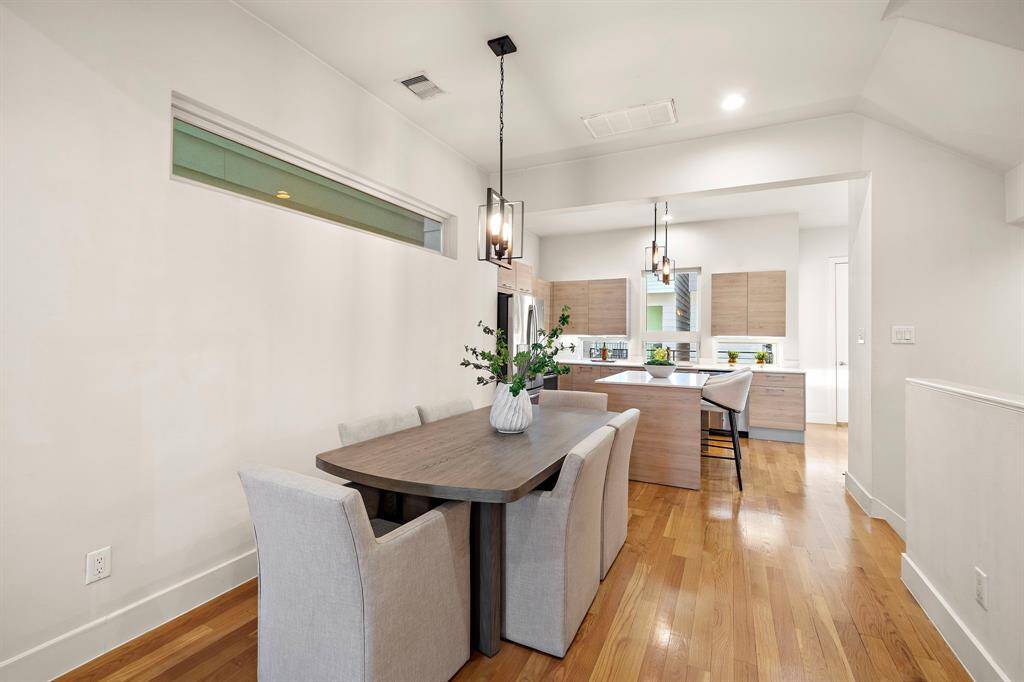 Sleek pendant lighting, warm hardwood floors, and neutral finishes create a sophisticated yet practical setting ideal for low-maintenance living.