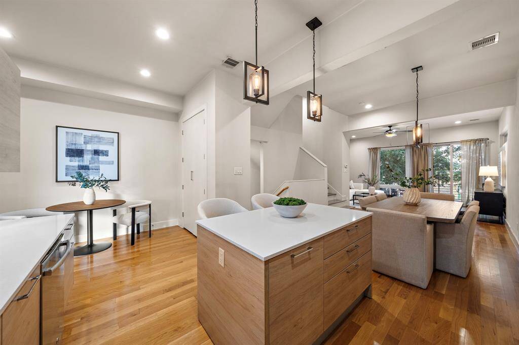 Bright kitchen layout features an oversized island with counter seating, pendant lighting, and contemporary cabinetry, seamlessly connecting to the breakfast area for casual dining.