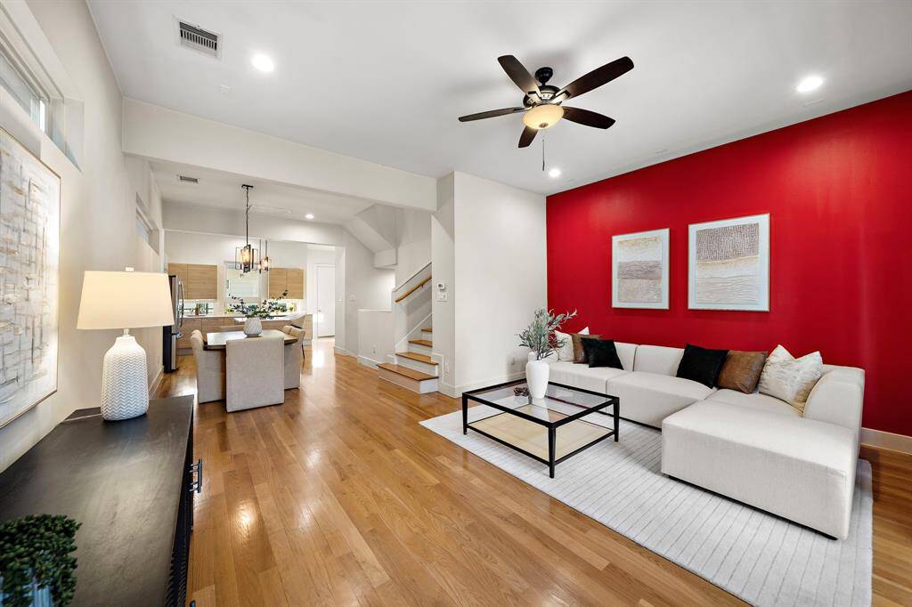 Spacious living area with abundant natural light, rich hardwood floors, and access to a private balcony. The open layout seamlessly connects to the dining and kitchen spaces, while a dramatic accent wall adds contemporary flair, ideal for both relaxing and entertaining.