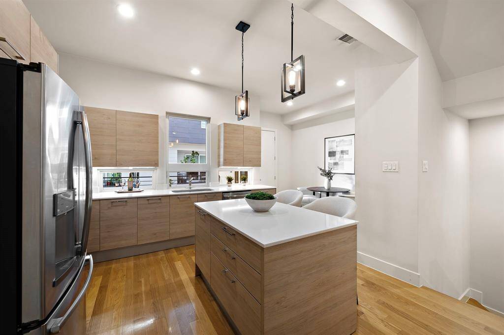 Contemporary kitchen and breakfast area blend seamlessly, highlighted by sleek flat-panel cabinetry, quartz countertops, and an oversized island with seating for casual dining.