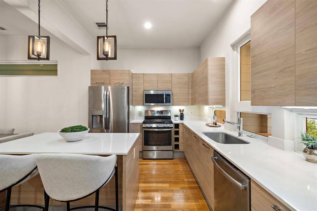 Modern kitchen features flat-panel cabinetry, a full suite of stainless appliances, and a gas range, anchored by an oversized island with built-in seating.