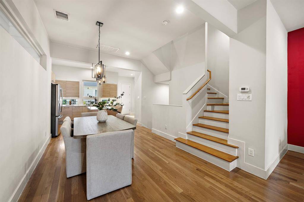 Modern dining area with neutral tones and warm hardwood floors sits adjacent to the sleek open kitchen.