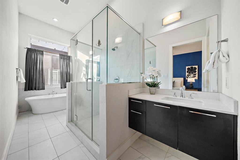 The primary bath boasts a freestanding soaking tub, a large glass-enclosed shower, and a floating double vanity with contemporary fixtures.