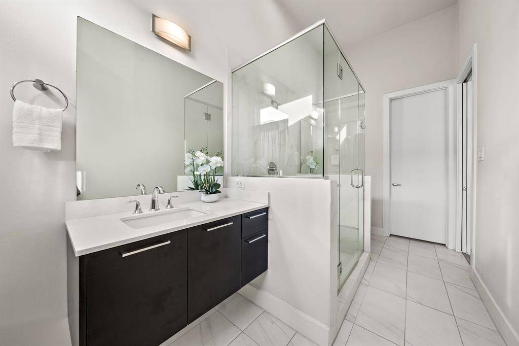 The floating double vanity with contemporary fixtures, polished stone counters, and large-scale tile flooring creates a clean, modern retreat with spa-inspired comfort.