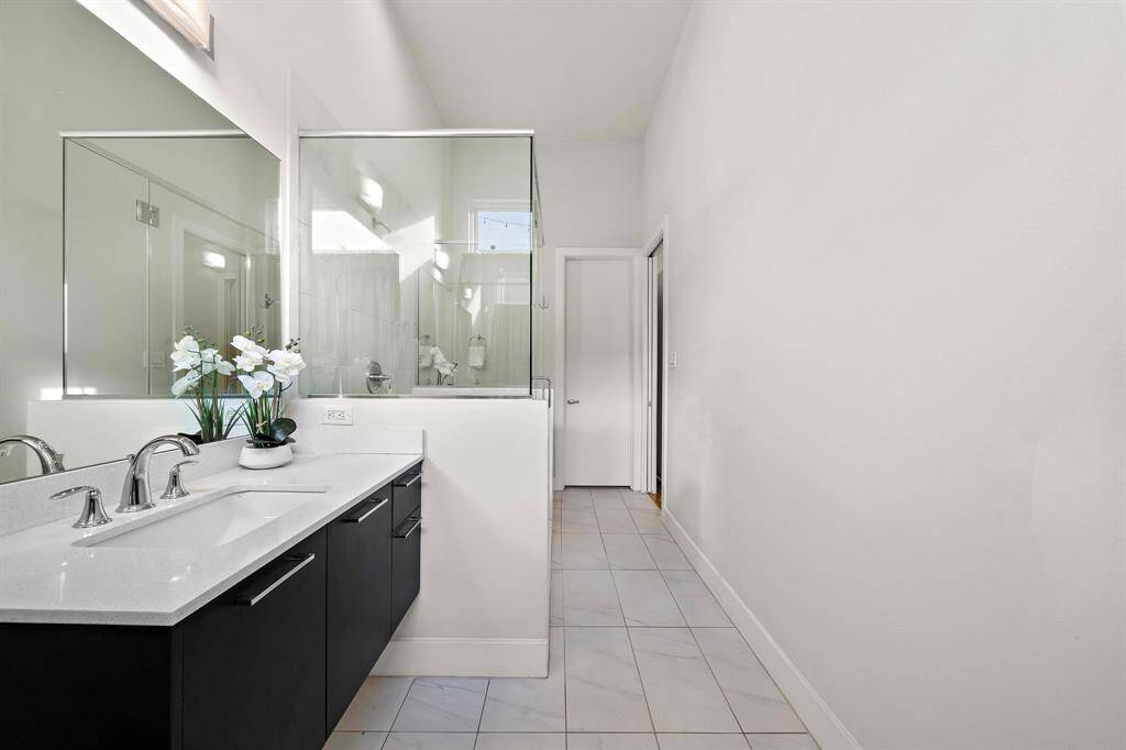 Contemporary ensuite bath features a floating vanity with sleek quartz counters, a frameless glass-enclosed shower, and modern fixtures.