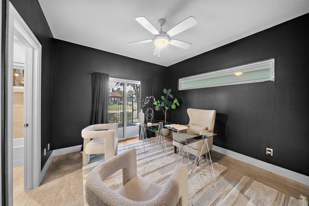Versatile ground-floor study or flex room offers a sleek, modern aesthetic with striking dark walls, tile floors, and a ceiling fan for year-round comfort. Glass doors provide seamless access to the gated courtyard, creating a productive or relaxing space with abundant natural light and urban views.