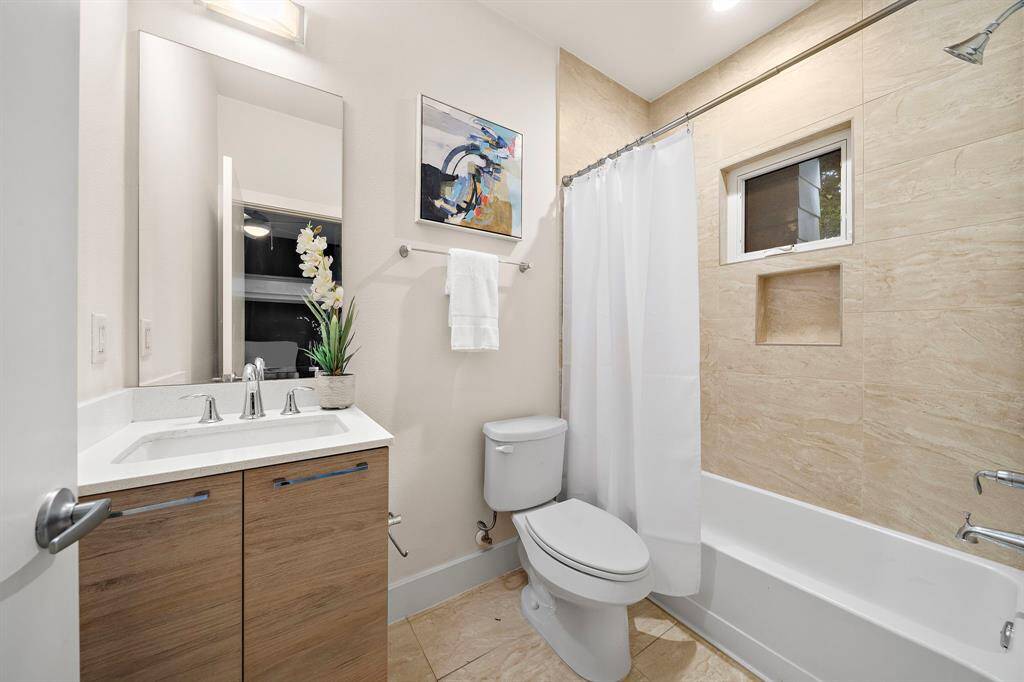 Modern full bath features sleek wood cabinetry, contemporary fixtures, and a quartz-topped vanity.