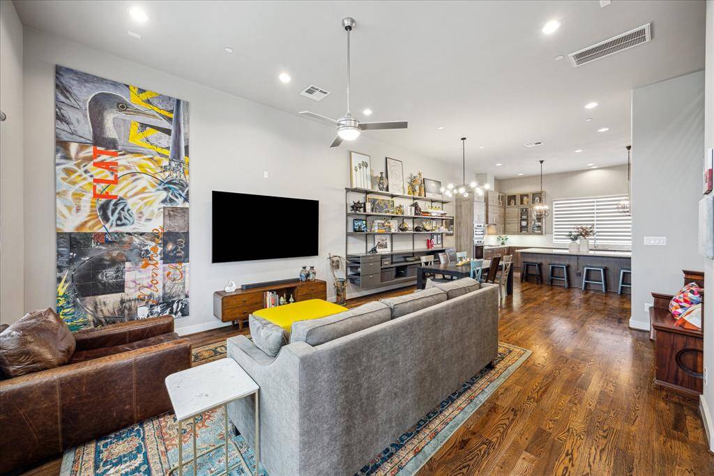 Designed for modern living, this open-concept space impresses with rich hardwood floors, an expansive kitchen with bar seating, and a spacious dining area, perfectly lit by contemporary fixtures and ideal for entertaining or everyday comfort.