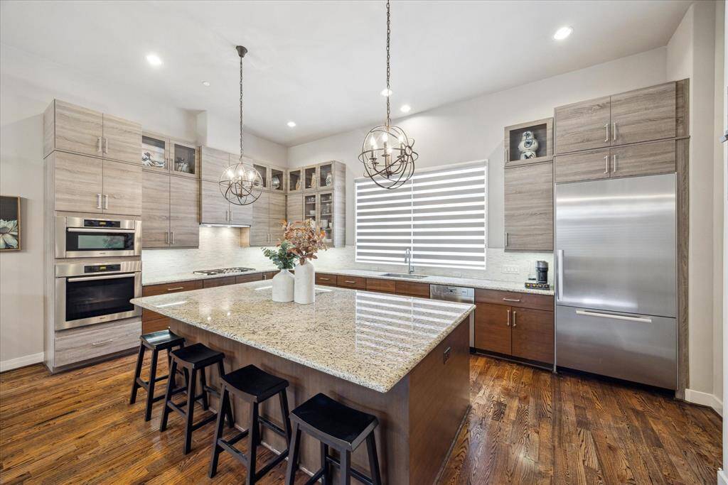Another view of this thoughtfully designed kitchen reveals its perfect balance of style and flow, ideal for everything from morning routines to evening gatherings. The granite island with bar seating invites casual dining, while recessed and pendant lighting accentuate the kitchen’s clean lines and welcoming feel.