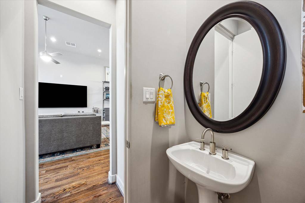 Perfectly positioned just off the main entertaining areas, this stylish powder room offers both convenience and charm. It features a contemporary pedestal sink and modern mirror, making it the ideal guest bath, thoughtfully placed to serve gatherings in the spacious and open concept living and dining areas.