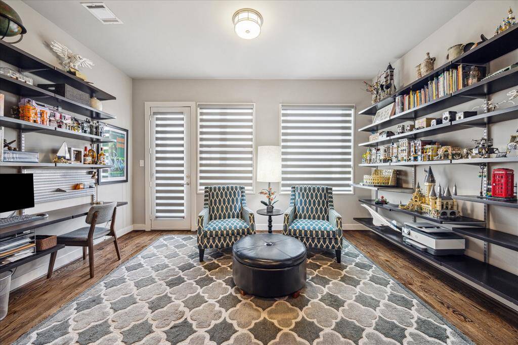 This inviting nook combines function and comfort with built-in shelving ideal for displaying books or personal collections, a dedicated workspace, and plush seating. Enhanced by large windows and a modern light fixture, it is the perfect space for quiet reading, focused work, or creative inspiration.