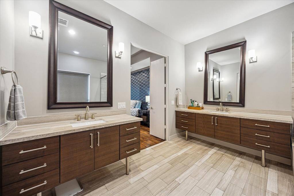 Another perspective of the spa-inspired primary bath highlights its refined symmetry and calming ambiance. Framed mirrors and dual sinks rest atop elegant wood cabinetry, while soft lighting and a soothing color palette complete the space, offering a perfect blend of function and tranquility.