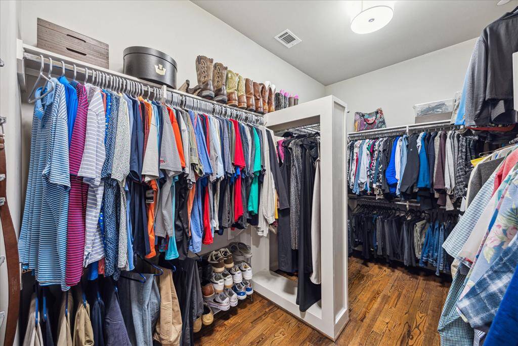 This expansive walk-in closet offers a beautifully organized space with abundant hanging areas, custom shelving, and dedicated storage for shoes and accessories. Thoughtfully designed with clean lines and warm flooring, it combines everyday functionality with boutique-style elegance.