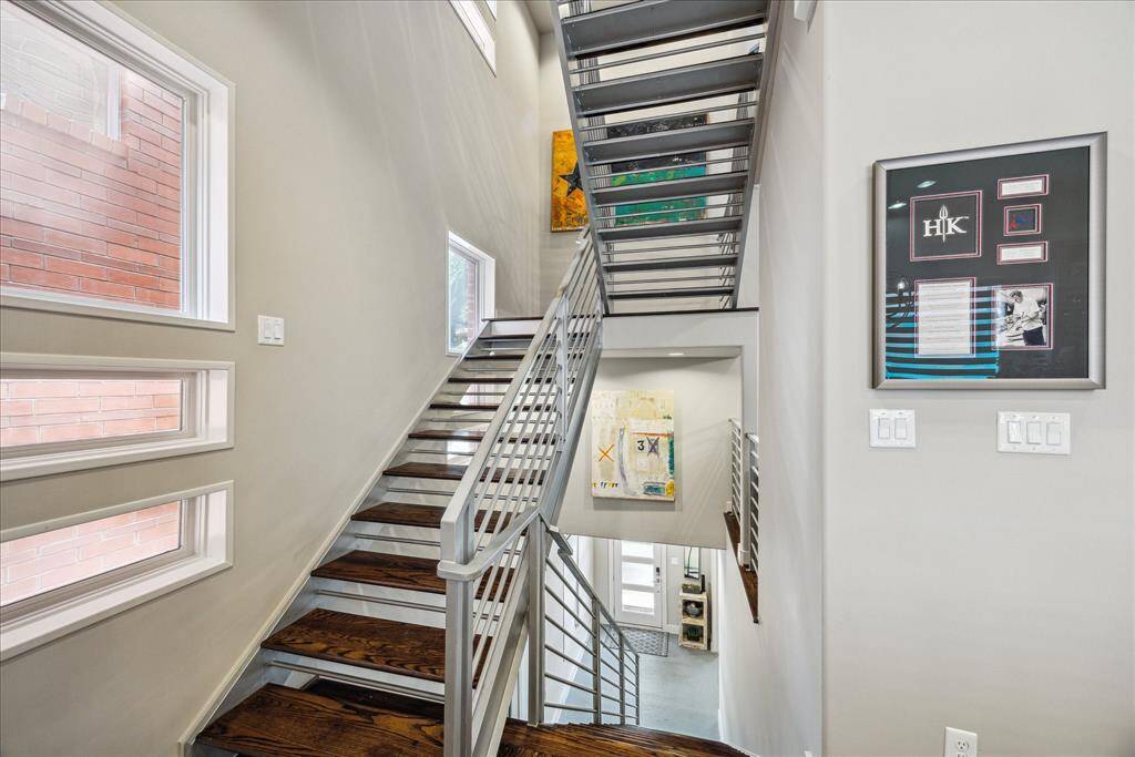 This striking staircase makes a bold architectural statement with its sleek metal railings and rich wooden steps. Connecting all four levels of the home, it is both a functional centerpiece and a design focal point. Generous wall space and natural light offer the perfect canvas for displaying art, creating a dramatic yet welcoming transition between living areas.