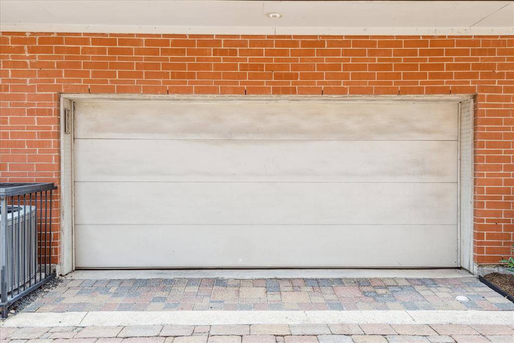 The attached two-car garage offers secure parking and additional storage, framed by a classic brick exterior and a paved driveway. In addition to the garage, abundant street parking is available, providing convenience for both residents and guests in this prime urban location.