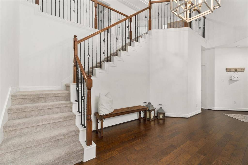 Elegant staircase leading to the upper level, featuring three spacious bedrooms, two modern bathrooms, a versatile game room, and a cozy media room. Recently updated with sleek countertops and plush new carpeting, offering both style and comfort.