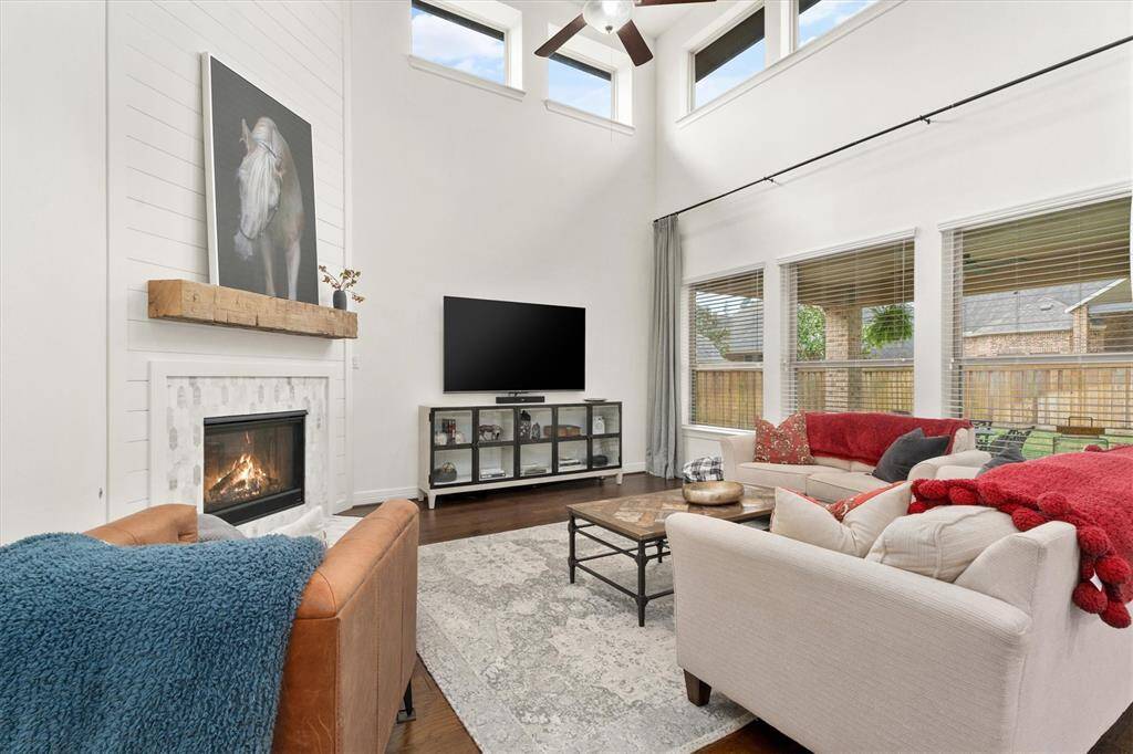 Step into this spacious and light-filled family room, where soaring ceilings and an abundance of windows create an airy, open feel. The centerpiece is the beautifully updated fireplace, showcasing modern shiplap detailing, an elegant tile surround, and a charming natural wood mantel – the perfect blend of style and warmth. Whether hosting guests or enjoying a quiet evening, this room offers the ideal setting.