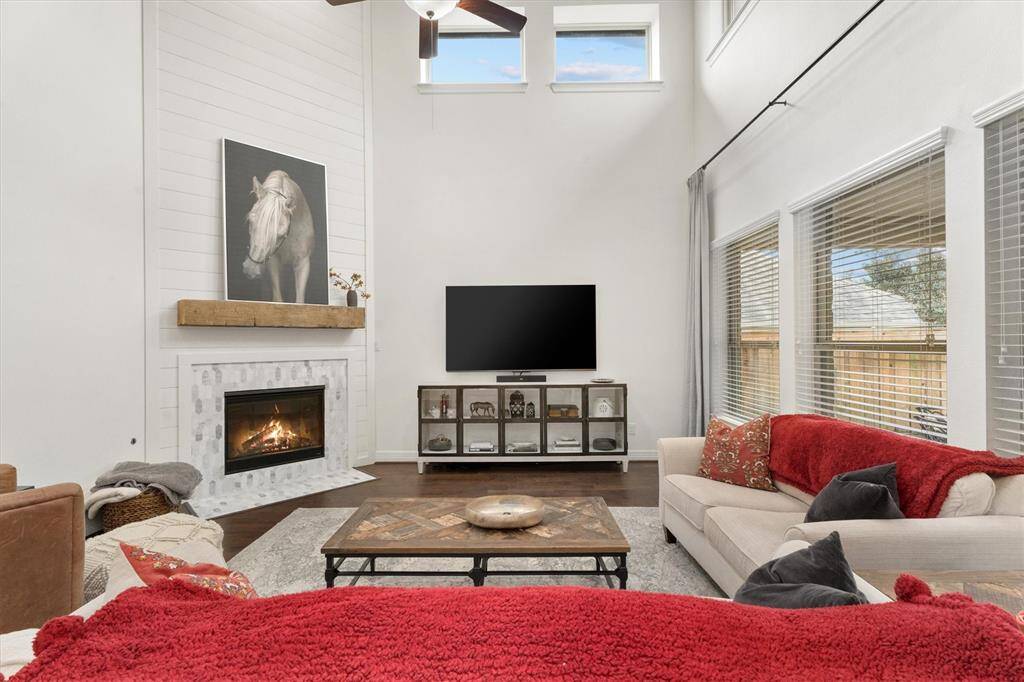 Step into this spacious and light-filled family room, where soaring ceilings and an abundance of windows create an airy, open feel. The centerpiece is the beautifully updated fireplace, showcasing modern shiplap detailing, an elegant tile surround, and a charming natural wood mantel – the perfect blend of style and warmth. Whether hosting guests or enjoying a quiet evening, this room offers the ideal setting.