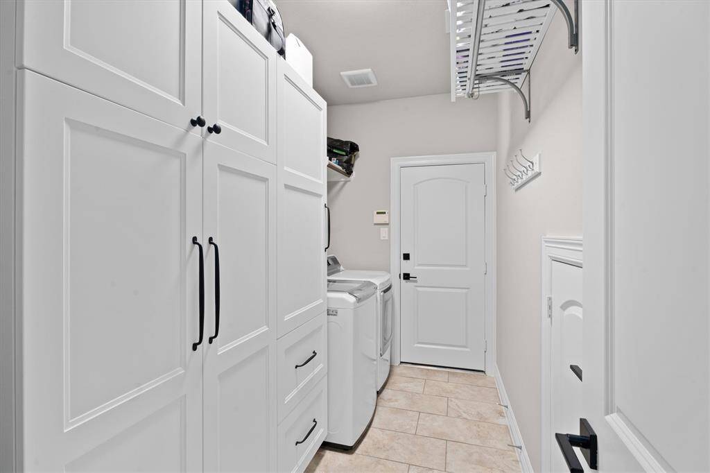 The well-appointed utility room offers exceptional storage with custom floor-to-ceiling cabinets, providing ample space to keep everything organized. Conveniently located with direct access to the garage, this functional space seamlessly blends practicality and style.