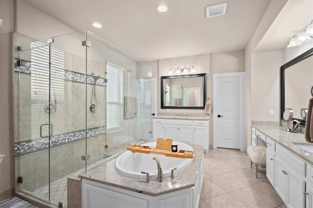 The spacious primary bathroom is designed for relaxation and convenience, featuring a luxurious soaking tub and a double-entry, walk-in shower. Dual vanities provide plenty of personal space, while the expansive walk-in closet is sure to impress with its ample storage. A thoughtfully designed retreat within your home.