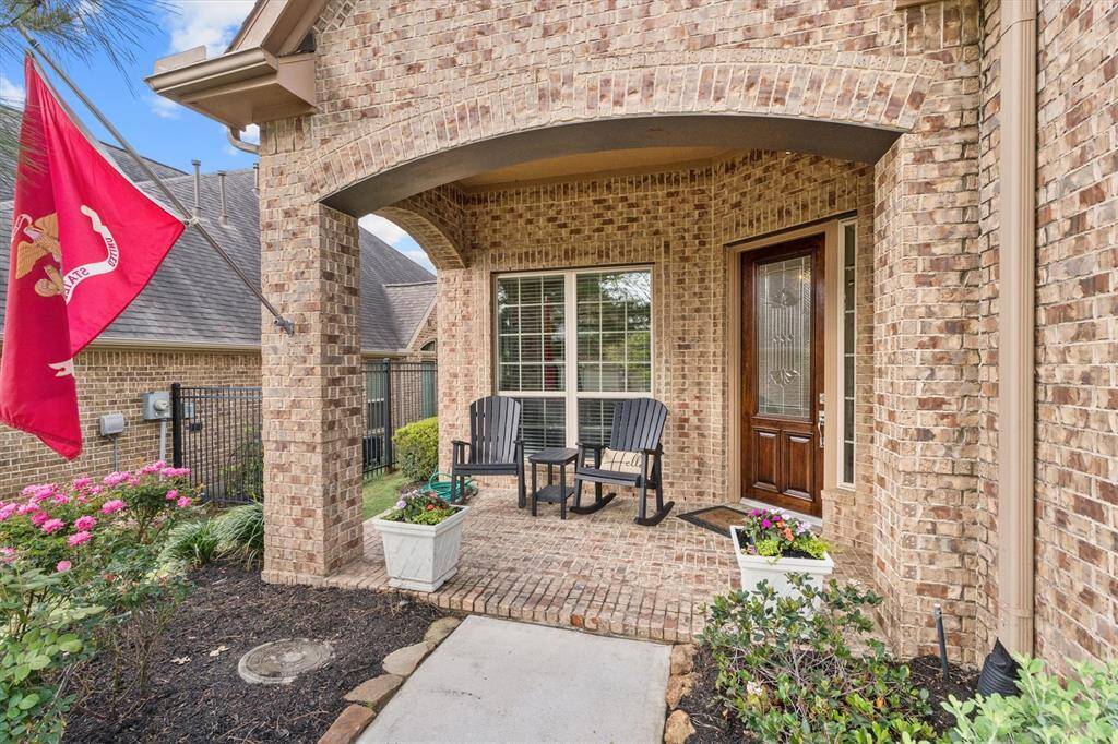 This spacious front patio offers a warm welcome with a cozy sitting area, perfect for morning coffee or evening relaxation. The freshly stained front door adds a touch of elegance, complementing the inviting atmosphere of this beautiful home.