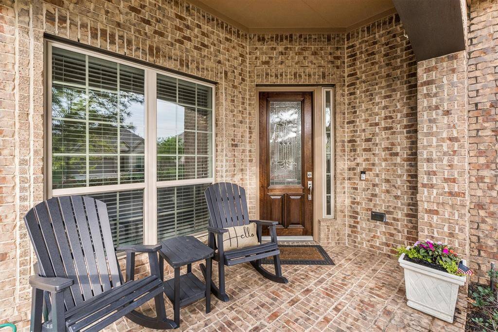 This spacious front patio offers a warm welcome with a cozy sitting area, perfect for morning coffee or evening relaxation. The freshly stained front door adds a touch of elegance, complementing the inviting atmosphere of this beautiful home.