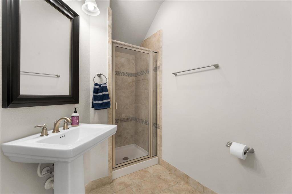 This full bathroom, conveniently located across from the downstairs secondary bedroom, features a modern stand-up shower, offering both style and functionality. It’s the perfect retreat for guests or family members, with easy access to the main living areas.