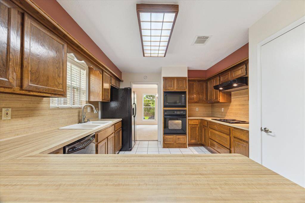 Designed for both everyday cooking and special occasions, this well-equipped kitchen features sleek black appliances, plenty of prep space, and abundant cabinetry with convenient pots and pan drawers. Whether you're hosting a crowd or simply making dinner, this space makes it easy to feel right at home.