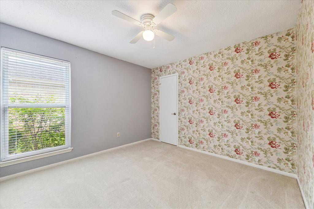 This inviting bedroom offers a quiet, comfortable space with neutral carpet, soft natural light, and a ceiling fan to keep things cool. It’s just right for family, guests, or anyone who needs a peaceful place to unwind.