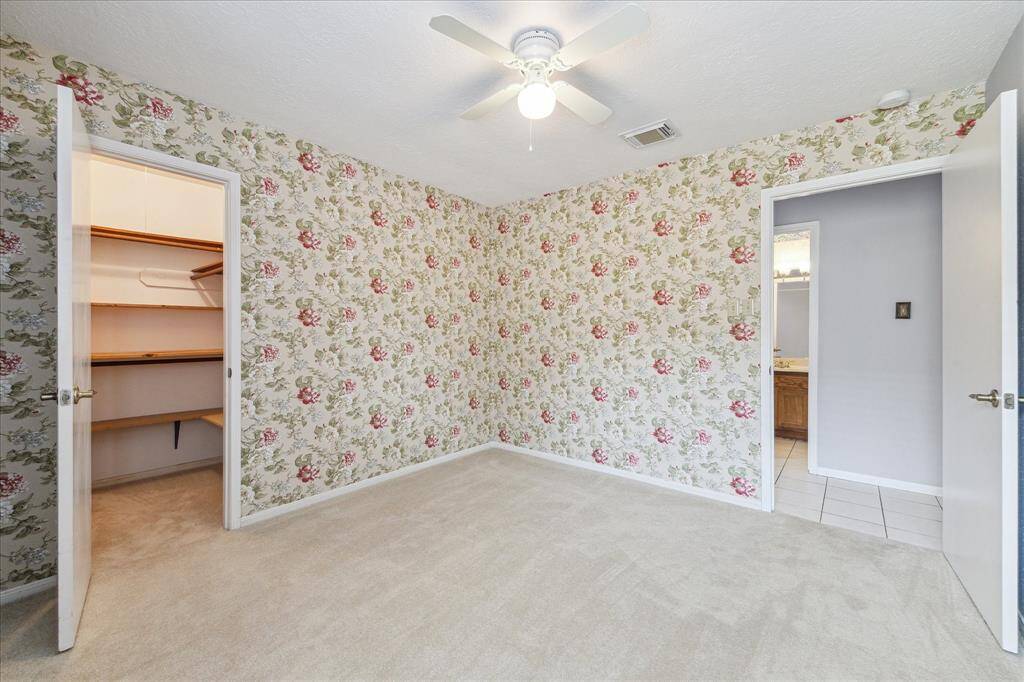 One more look at this spacious bedroom highlights the generous walk-in closet, complete with built-in shelving offering plenty of space to keep everything organized and easy to access.