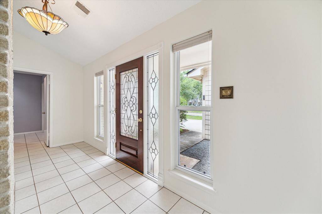Welcome home! A beautiful leaded glass front door and sidelights set the tone for this inviting entryway, where tile flooring, soft neutral tones, and a stylish chandelier create a lasting first impression.
