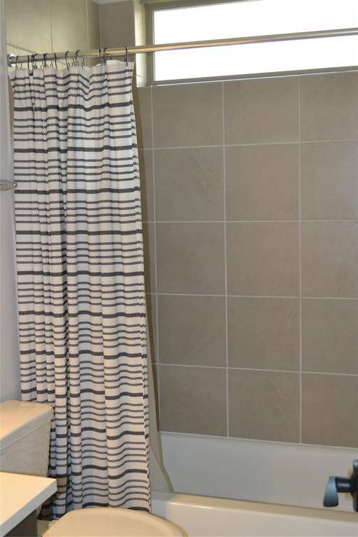 One of the bathroom features bathtub with neutral porcelian tile.