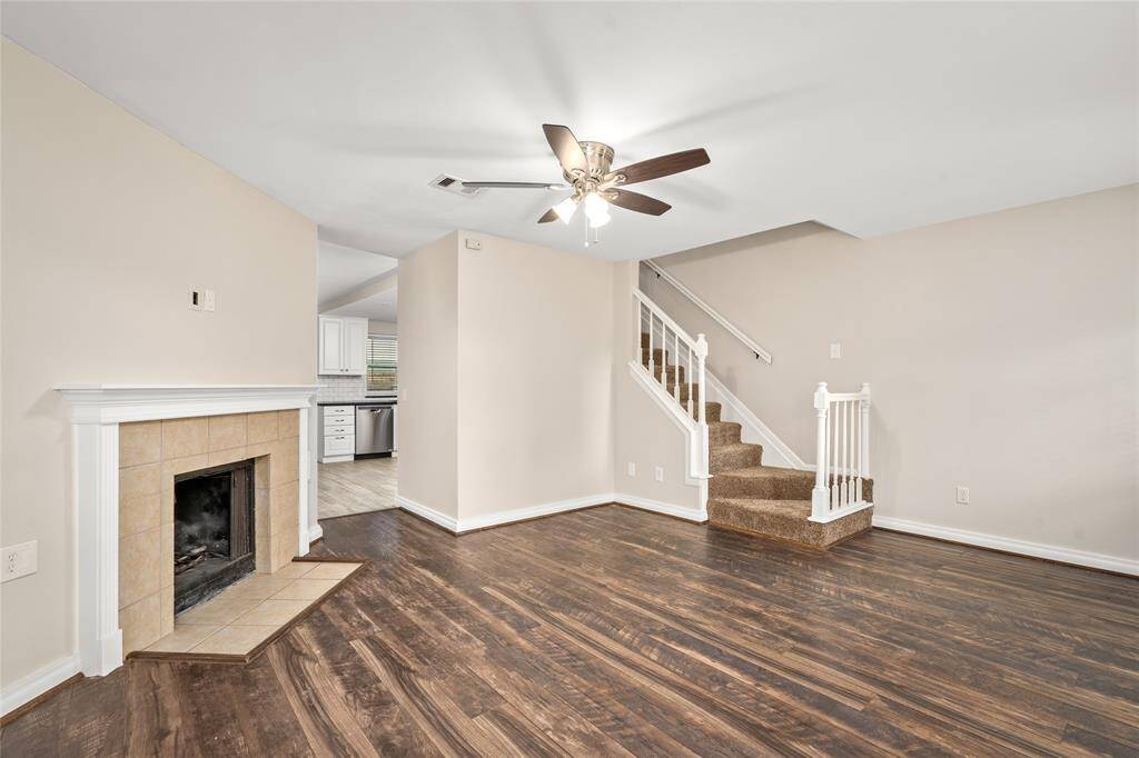 Open-concept living area with a clear view of the staircase leading to the second level. The layout offers great flow between levels, with neutral tones, rich flooring, and crisp white trim adding to the home's clean and modern feel.
