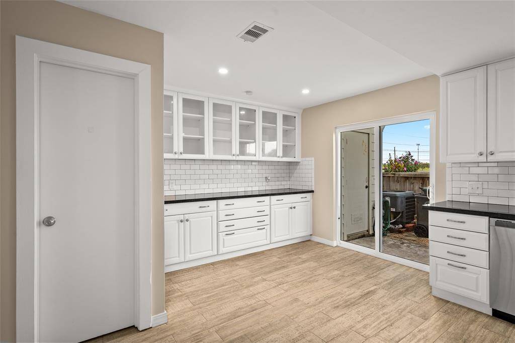 Enjoy cooking in this beautifully remodeled kitchen with crisp white cabinets, stainless steel appliances, and a sleek subway tile backsplash. The spacious layout flows seamlessly to the patio through large sliding glass doors, perfect for indoor-outdoor living.