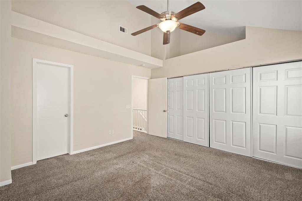 Spacious and well-lit, this upstairs Primary bedroom features plush carpet flooring, neutral wall tones, and a modern ceiling fan with light. A full wall of double-door closets provides generous storage, while the vaulted ceiling adds a touch of architectural interest. Conveniently located near the landing, this room offers comfort and functionality.