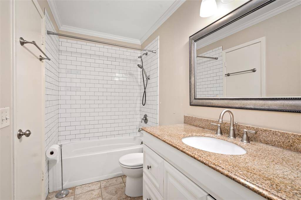This well-appointed upstairs bathroom features a sleek combination of classic and modern finishes, including a white subway tile shower surround, brushed nickel fixtures, and a granite vanity top. The large framed mirror and neutral tile flooring complete the space, offering both functionality and timeless style