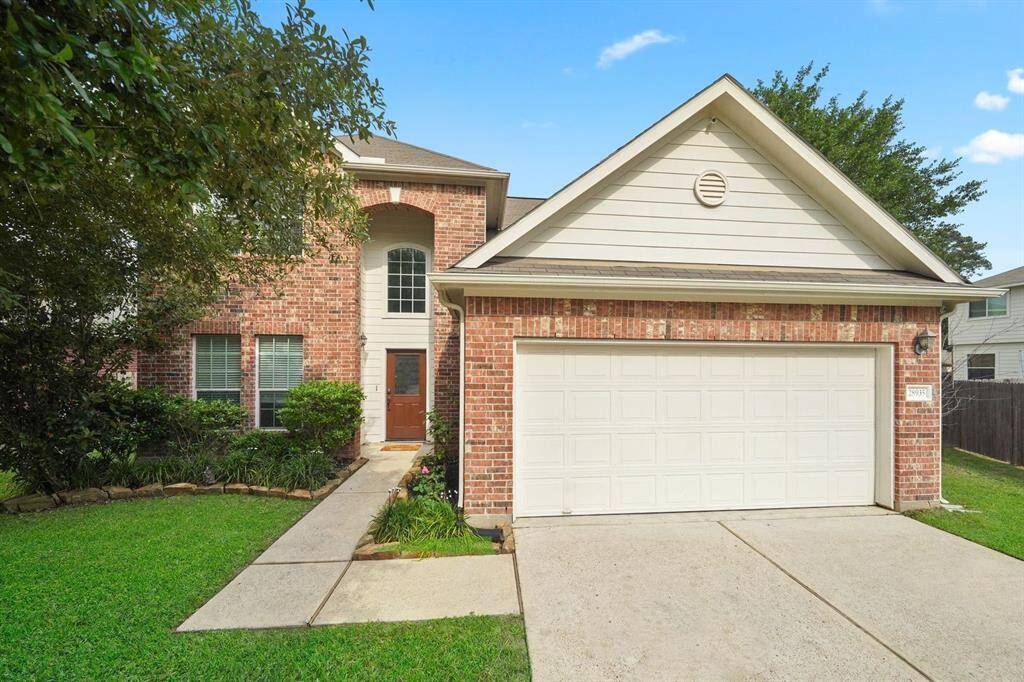 Two-story brick home with an attached two-car garage. The architecture includes a high entryway and a combination of brick and siding on the facade. Home is located in a suburban neighborhood in Magnolia.