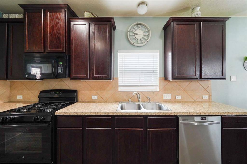 Dark wood cabinets, tile backsplash, and new microwave and new sink (not shown in this photo). The cook of the family will appreciate the gas stove.