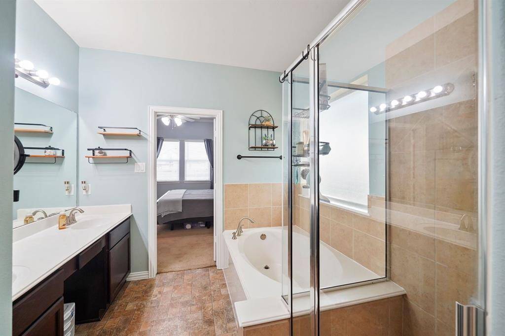 Tile flooring and tile surrounding the glass-enclosed shower and a separate soaking tub creates a clean and relaxing primary bathroom.