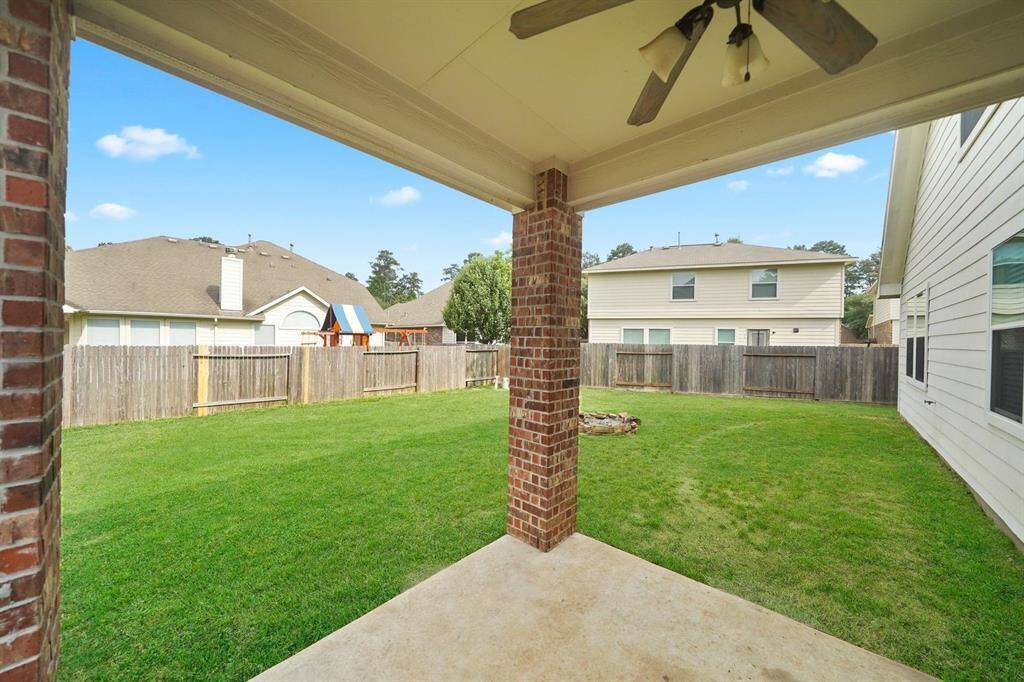This is a view from the covered patio looking out onto a spacious, fenced backyard offering a private outdoor space suitable for relaxation and activities.