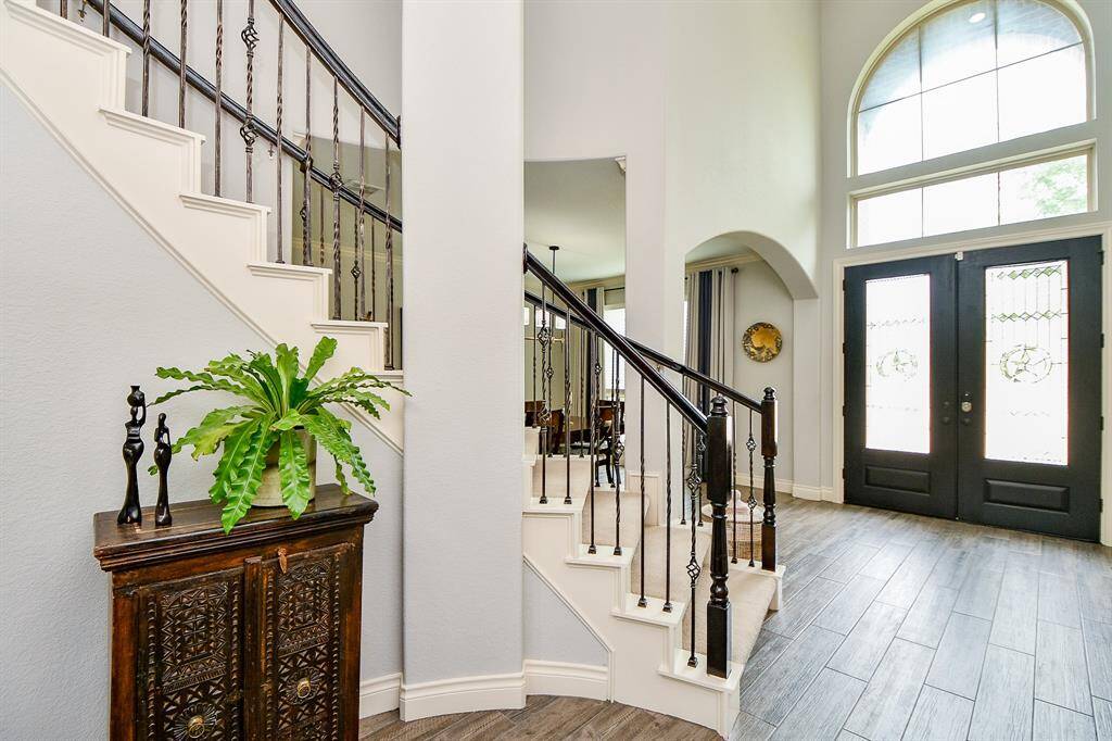 Heavenly high ceilings, sophisticated pale wall tones; neutral, durable wood look tile flooring provide this rich view of the main entry from the inside and provides a grand entrance to you and your guests. Welcome home!”