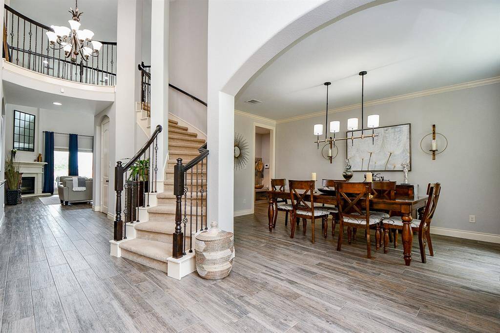 This open view from entry to the family room with visual delights, the introduction of the grand spiral staircase, formal dining space, right; vaulted ceilings and column detail.