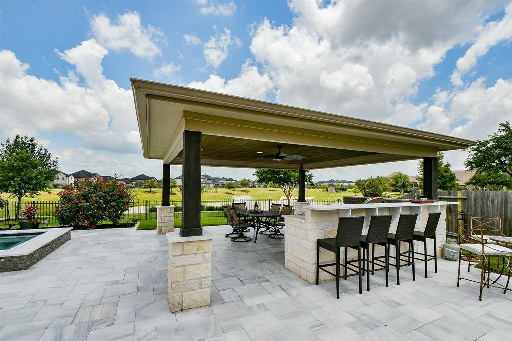 Resort-style outdoor pavilion located poolside, perfect for entertaining or relaxing in the shade. Features ample seating space, ideal for al fresco dining, weekend gatherings, or enjoying the tranquil view of the pool and surrounding landscape."