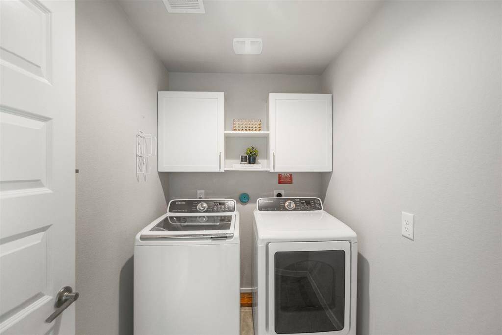 The laundry room includes  a tile floor and cabinet storage, and it is conveniently located next to the kitchen.