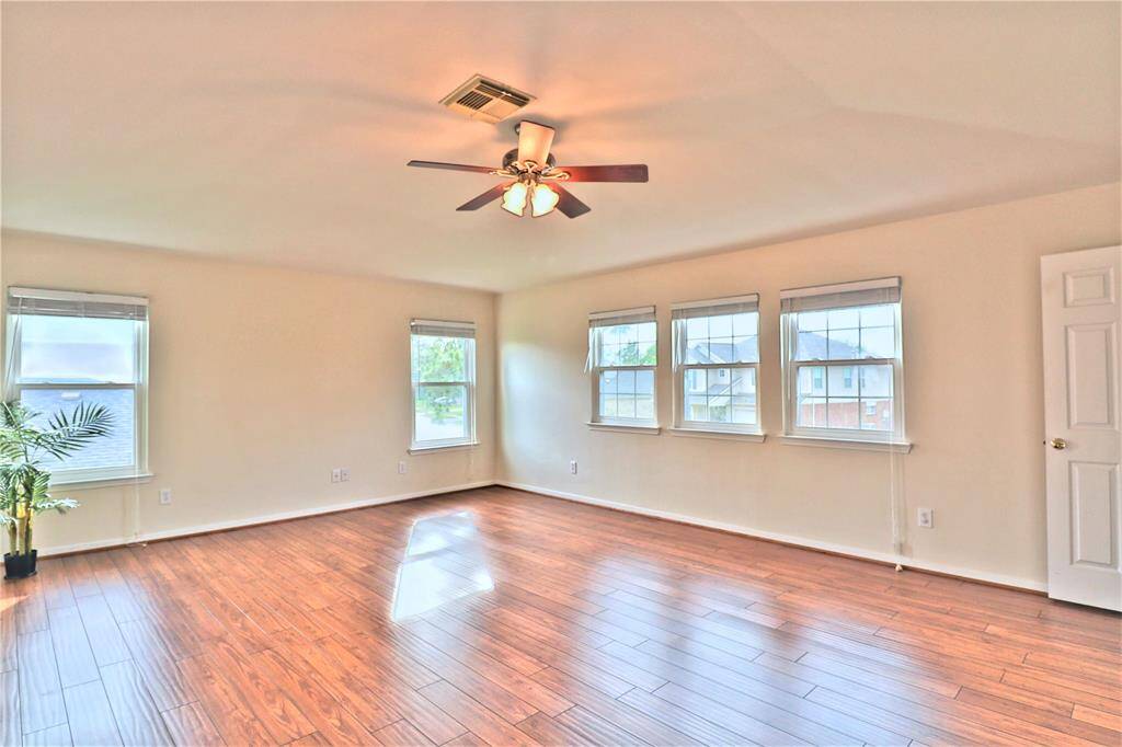 Spacious primary bedroom with ample natural light and a ceiling fan.