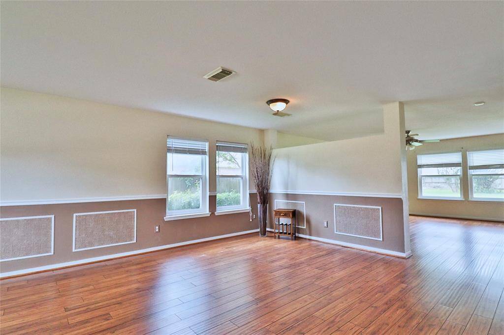 bright, open living and dinning area with decorative paneling, wood flooring. Large windows allow natural light to fill the room.